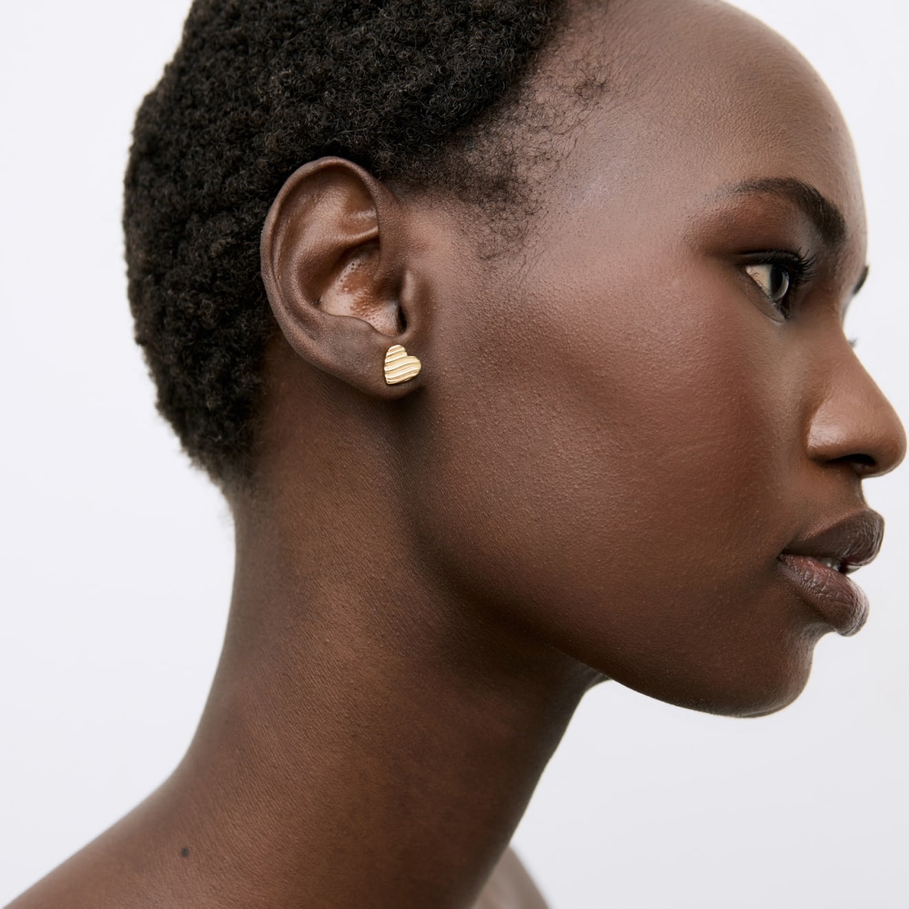 Model wearing a gold heart stud earring 